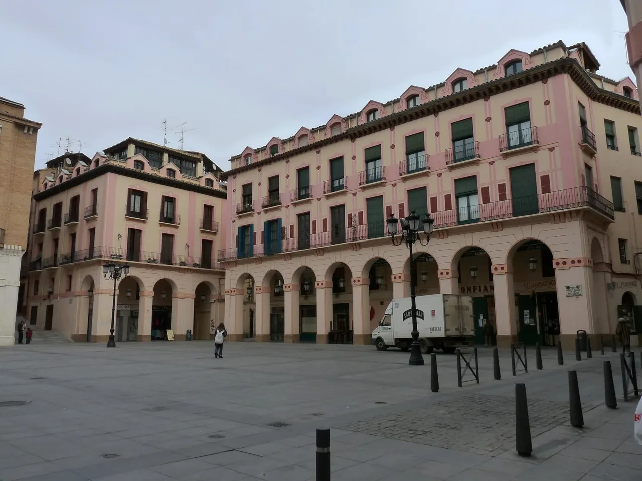 Soportales y fachadas rosadas de la plaza Luis López Allué en Huesca